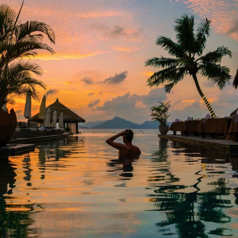 men-at-a-swimming-pool-at-a-luxury-hotel-at-sunset-over-the-ocean-luxury-pool-tropical-resort-e1704707686469.jpg