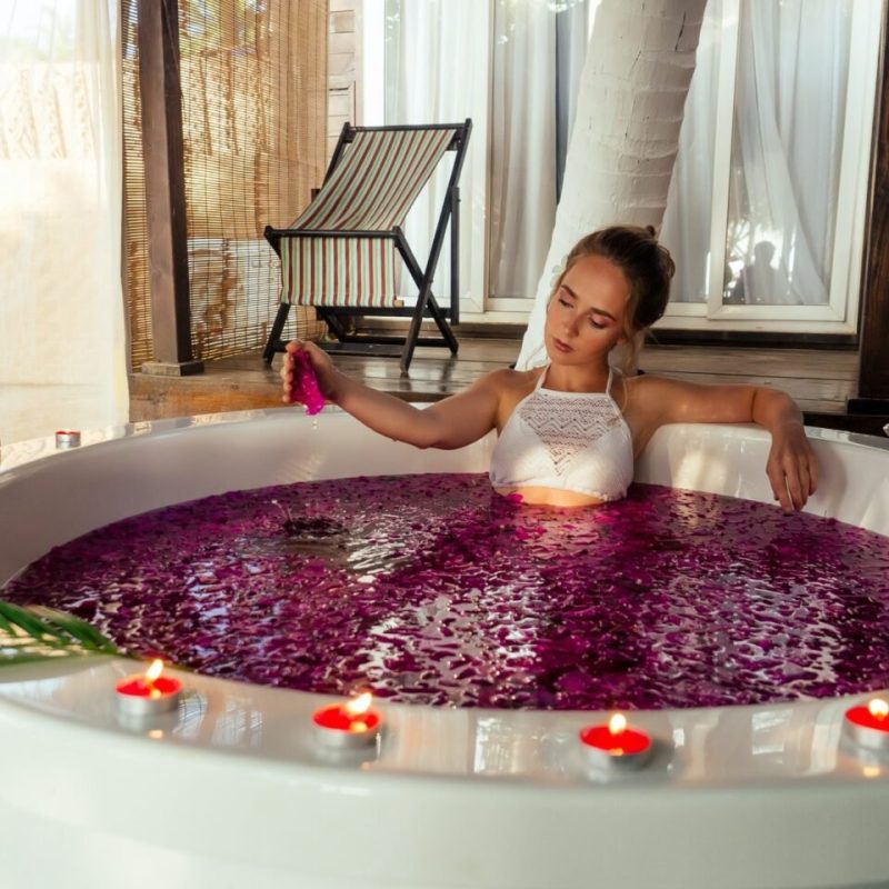 woman-relaxing-in-bath-with-tropical-flowers-outdoor-at-luxury-hotel-e1704707713643.jpg